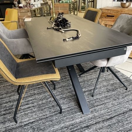 Grauer Tisch mit gemischten Stühlen steht auf einem grauen Teppich