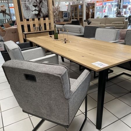 Holztisch mit grauen Stühlen steht im Ausstellungsraum