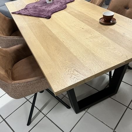 Holztisch mit braunen Stühlen steht im Ausstellungsraum