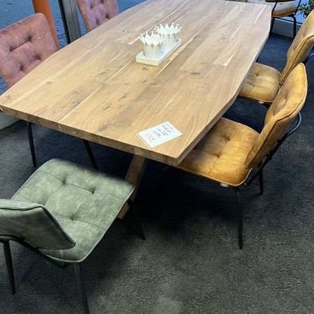 Tisch mit einer massiven Echtholzplatte und bunten, gemischten Stühlen steht im Ausstellungsraum