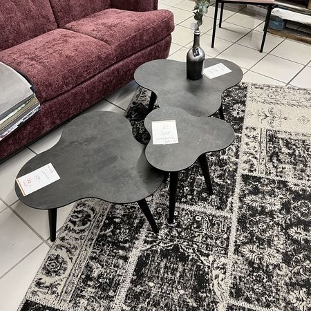 3 dunkelgraue Beistellstische stehen vor einem roten Sofa