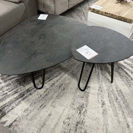 Ein zweiteiliger Couchtisch in grau steht auf einem Teppich