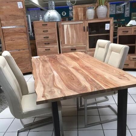 Ein Holztisch mit weißen Stühlen steht im Ausstellungsraum