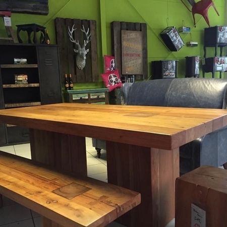 Ein Holztisch mit passenden Holzbänken steht in einem Verkaufsraum
