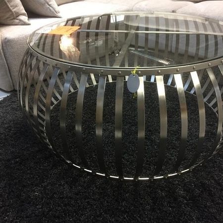 Ein Glastisch mit Metall steht auf einem dunklen Teppich
