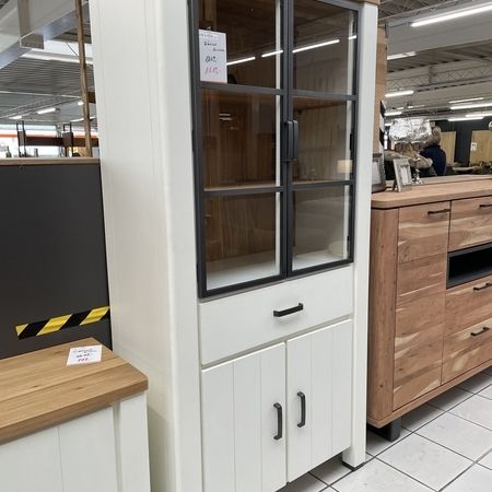 Ein weißer Holzschrank mit Vitrine, zwei Schranktüren und einer Schublade