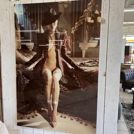 Ein glänzendes Bild von einer Frau die mit einem Hut auf einem Bett sitzt
